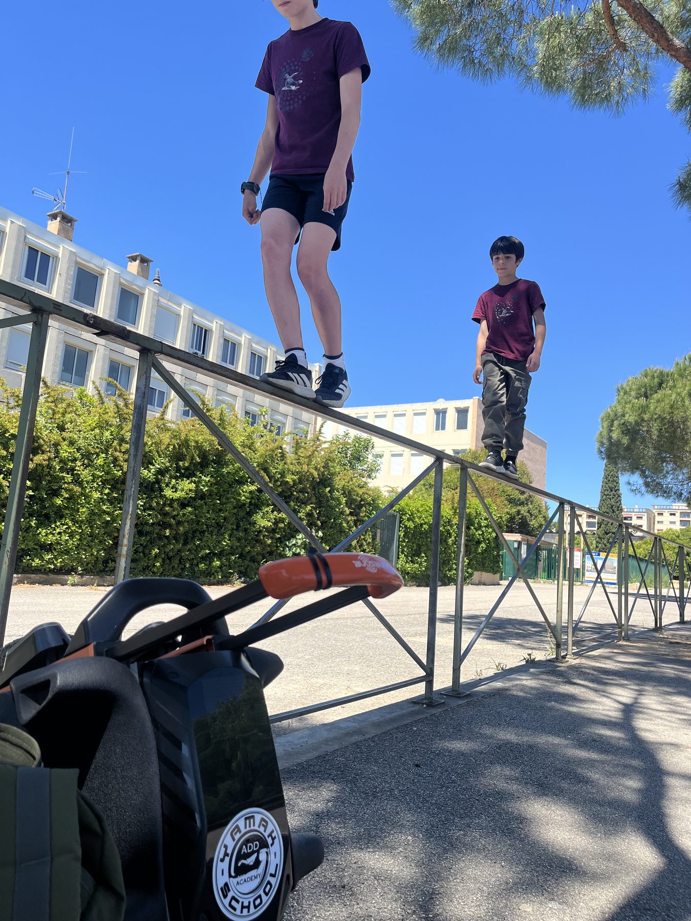 Deux jeunes en équilibre sur une rambarde, ciel bleu